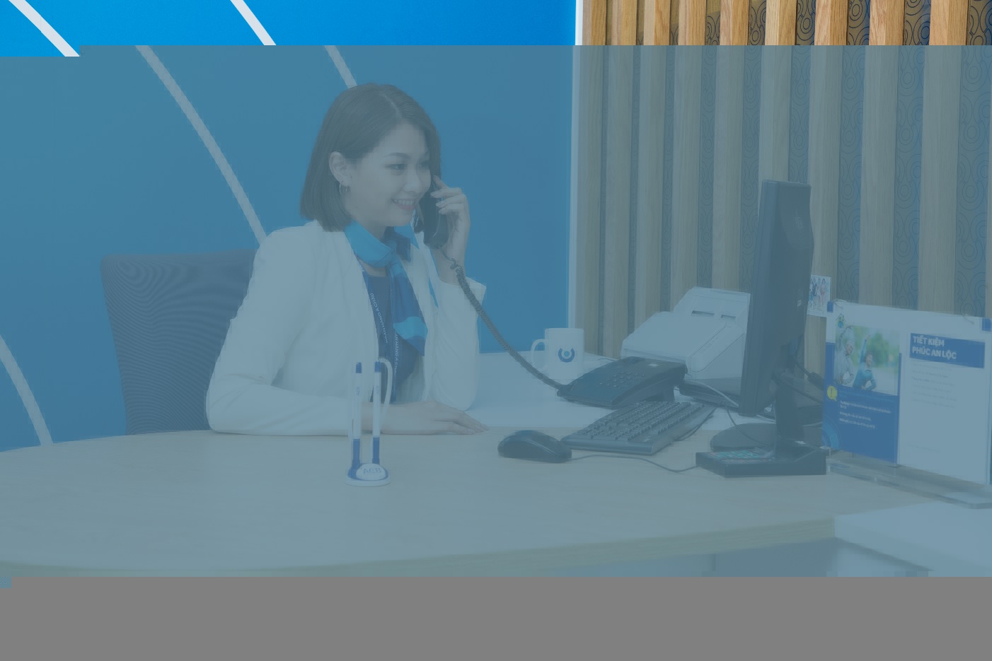 A person sitting at a desk talking on the phone  Description automatically generated