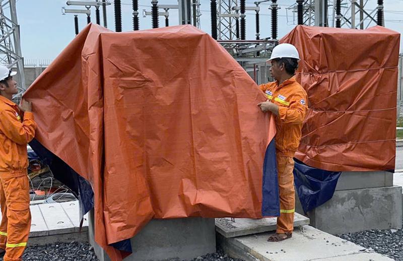 Công nhân đang che chắn thiết bị tránh mưa gió