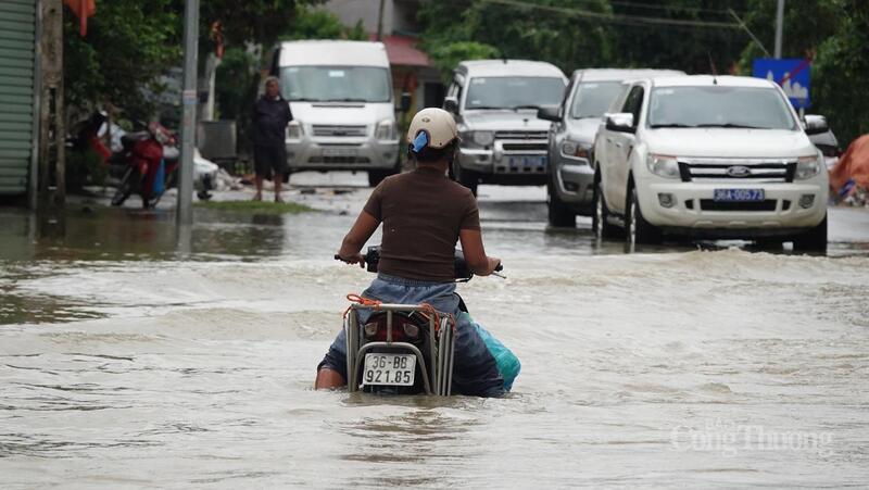 Nước sông Chu lên cao, tràn vào đường quốc lộ cũng khiến người dân vật lộn, bì bõm trong nước
