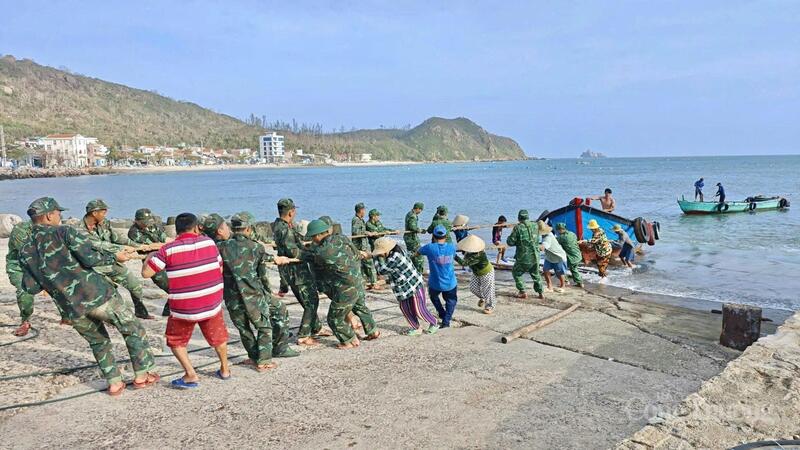 Các cán bộ, chiến sĩ hỗ trợ người dân đưa thuyền thúng lên bờ và hướng dẫn tàu thuyền trú tránh an toàn.