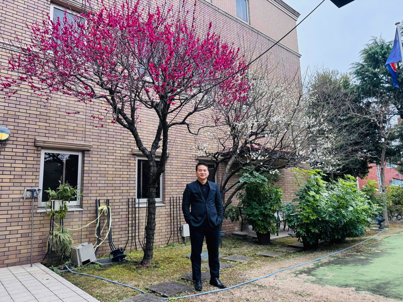 Tham tán thương mại Tạ Đức Minh chụp cùng cây hoa đào nở rộ đúng dịp Tết cổ truyền Việt Nam. Cây đào được trồng trong khuôn viên Đại sứ quán Việt Nam tại Nhật Bản.