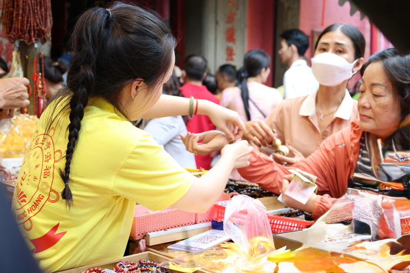 Không chỉ dâng lễ, nhiều người dân và bạn trẻ còn tìm mua các loại vòng tay, vật phẩm phong thủy tại quầy lưu niệm trong khuôn viên chùa để cầu may mắn và bình an. Ảnh: Minh Anh