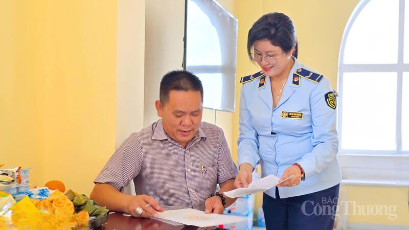 Các cán bộ Quản lý thị trường hướng dẫn các hộ kinh doanh ký bản cam kết chấp hành pháp luật về giá, an toàn thực phẩm.